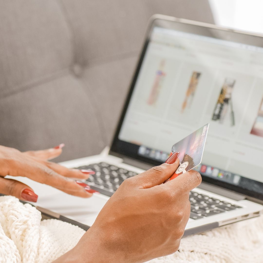 A woman shopping on her computer while holding her credit card